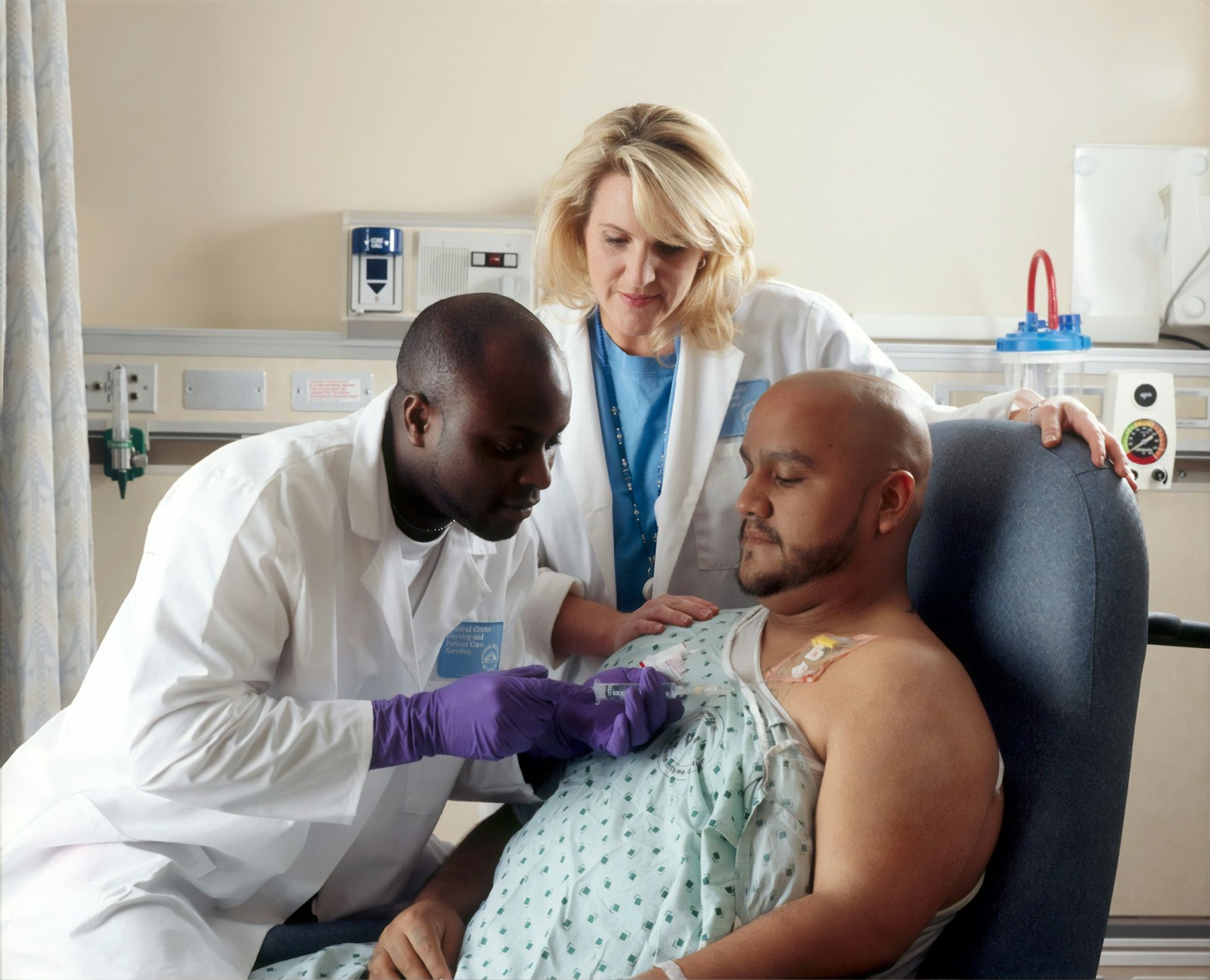 A doctor giving an injection to a man in a treatment chair while a nurse watches